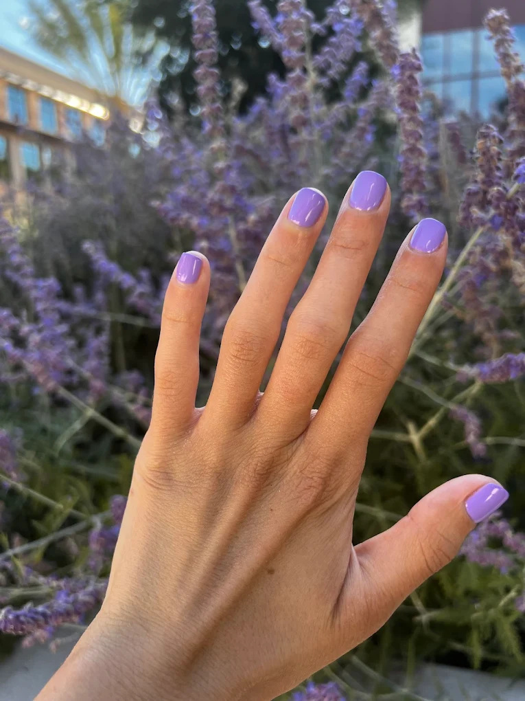 Soft purple manicure against a field of lavender flowers