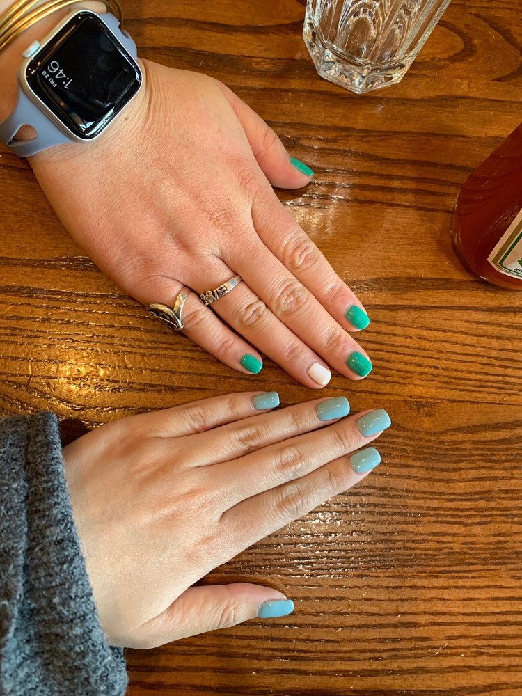 Mint green nails resting on a warm wooden table